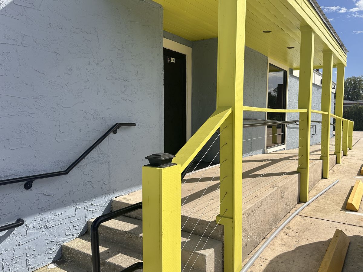 The porch walkway with lime posts, cable railings and steps up from the parking lot