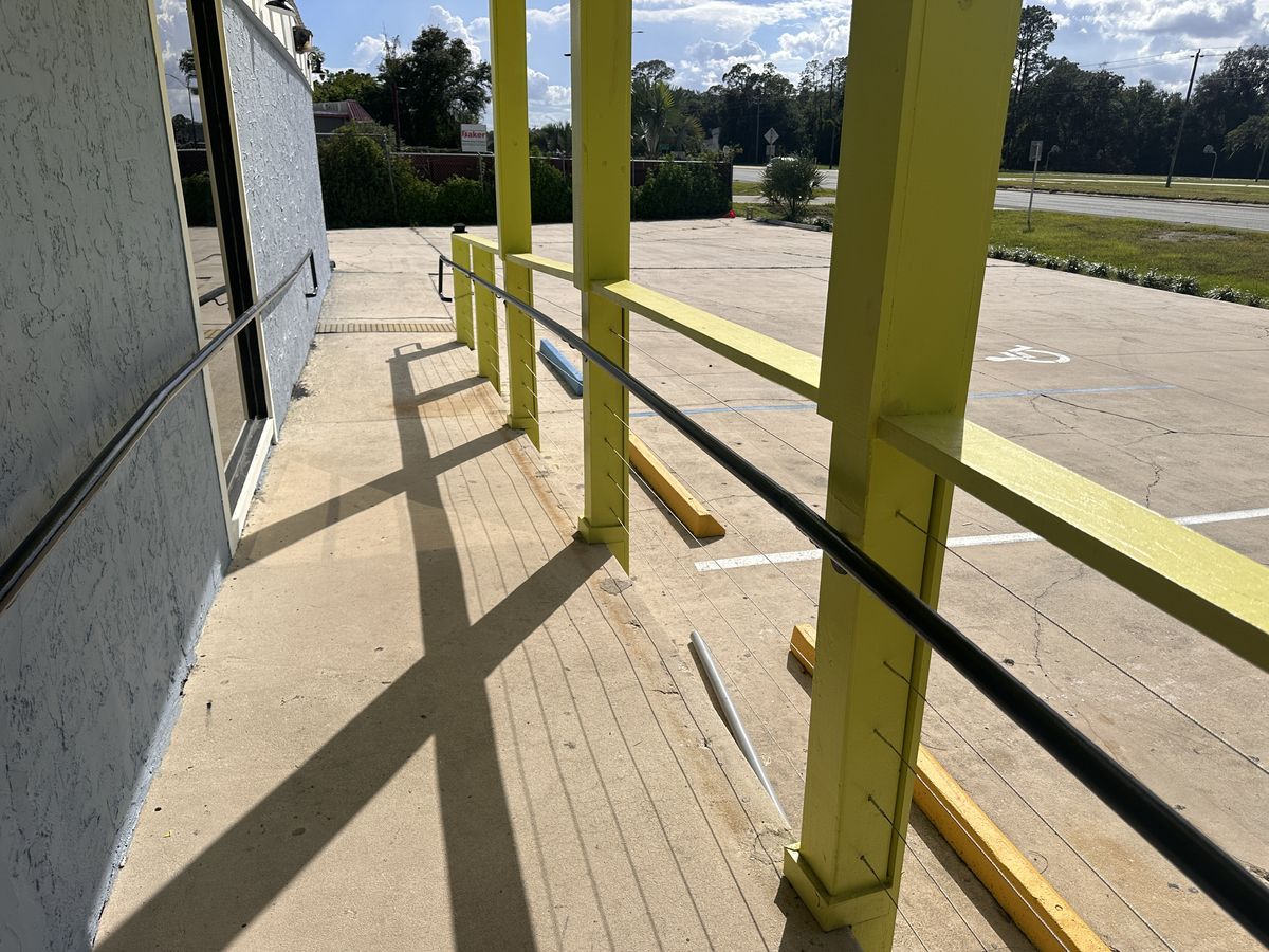 The entry ramp with lime railings and a black handrail, looking out over the parking lot